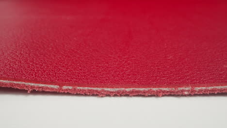 seam on edge of red cow leather material on white table