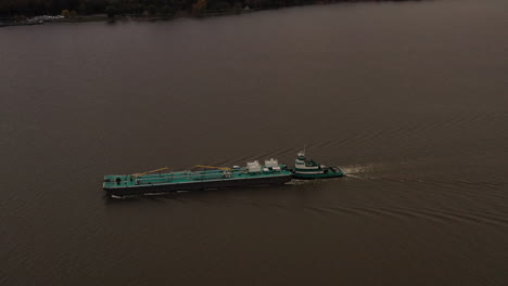 Toma-Aérea-Sobre-Una-Barcaza-De-Color-Turquesa---Remolcador-En-El-Río-Hudson-En-Un-Día-Nublado-En-Beacon,-Ny