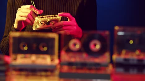 woman's hands are seen winding the tape on a vintage cassette with a display of cassettes in the foreground - sliding view with focus on the woman