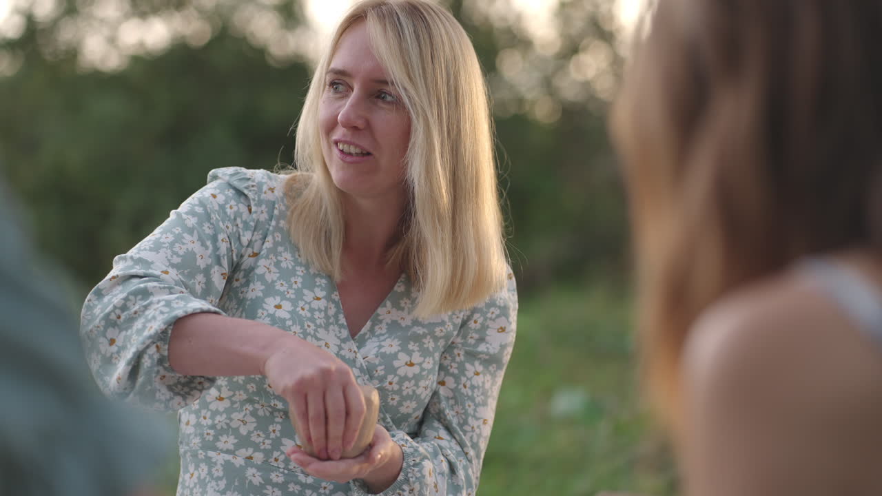 Young women make clay products in nature in the park in the open space. One girl laughs in close-up. Group classes women's circle communication humor fun joint creativity.