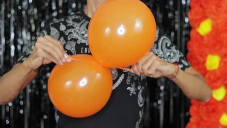 Tying-together-two-inflated-orange-balloons-for-Halloween-decoration