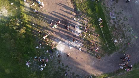 Toma-Aérea-De-Arriba-Hacia-Abajo-De-Los-Estudiantes-Que-Celebran-La-Graduación-Al-Aire-Libre-Con-Confeti-Y-Bombas-De-Pintura