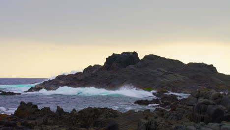 Plano-Amplio-De-Las-Olas-Del-Océano-Rompiendo-Contra-La-Costa-Rocosa-Del-Desierto-De-Atacama,-En-El-Norte-De-Chile,-Puesta-De-Sol.