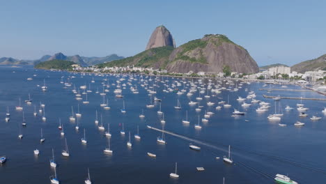 Imágenes-Aéreas-Siguiendo-Una-Lancha-Rápida-Navegando-Entre-Veleros-Anclados-Tanto-En-La-Bahía-De-Fogo-Como-En-Río-De-Janeiro,-Brasil.