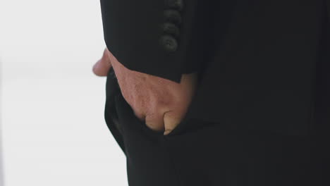 businessman in black jacket puts hand into pocket in office