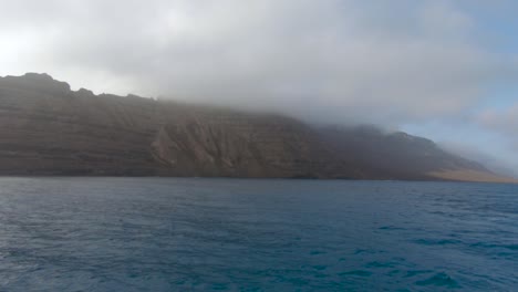 rocky cliff at the north coast of lanzarote in front of la graciosa in canary islands, spain. aerial