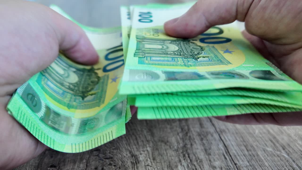un hombre sostiene y cuenta rápidamente los billetes de euro