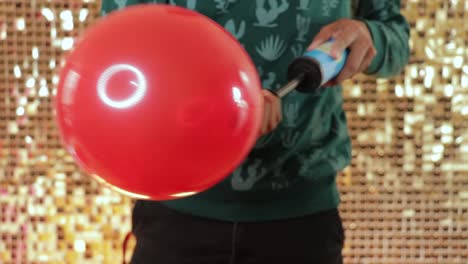 using a manual pump to inflate a red latex balloon