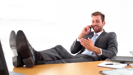 relaxed businessman putting his feet up talking on the phone