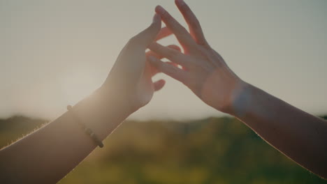 female friends touching hands against sky