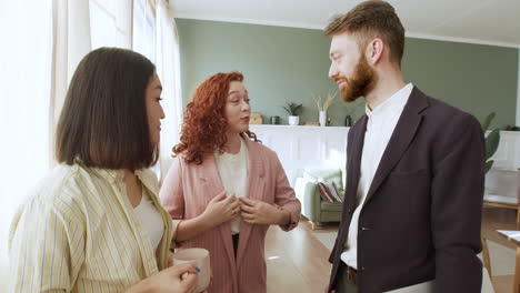 three multiethnic friends standing in the living room and talking together 1