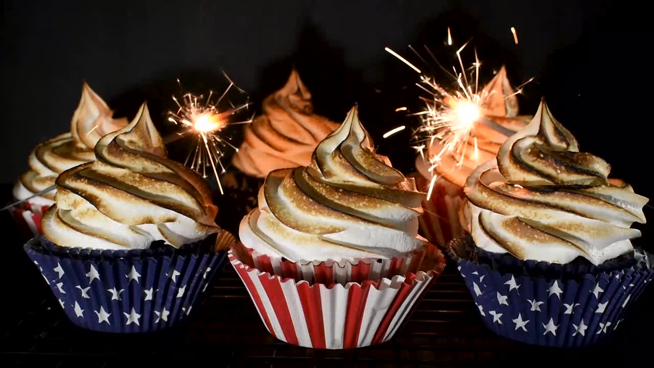stelle filanti che esplodono intorno a cupcake rossi bianchi e blu con la parte superiore a spirale di meringa tostata