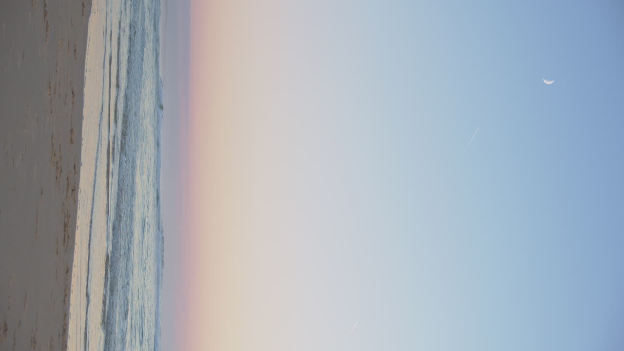 Vertical Shot Of Ocean With Pastel Horizon At Sunrise