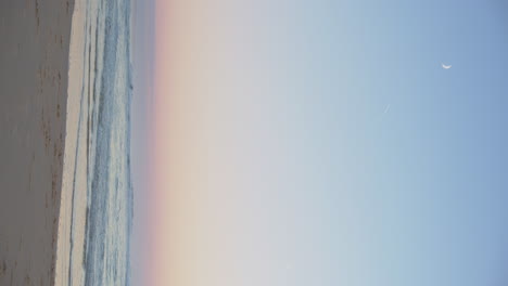 vertical shot of ocean with pastel horizon at sunrise