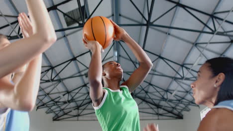 playing basketball, female athletes reaching for ball during game in indoor court