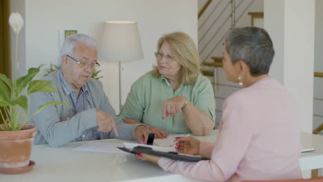 senior couple sitting at table, talking with realtor and discussing details of agreement