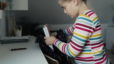 caucasian elementary girl packing schoolbag for school