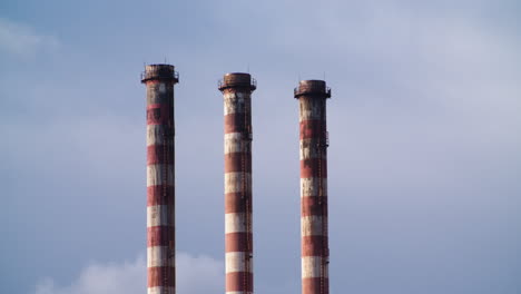 three pipes industrial chimneys on blue sky background, day, static