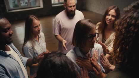 Una-Chica-Con-Corte-De-Pelo-Bob-Y-Gafas,-Con-Los-Ojos-Cerrados,-Se-Apoya-En-Los-Participantes-De-La-Terapia-De-Grupo,-Quienes-A-Su-Vez-La-Pasan-Al-Círculo.-Practicar-La-Confianza-En-La-Terapia-De-Grupo