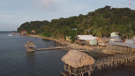 golden hour flight past grass thatch roof beach dock cabanas in roatan