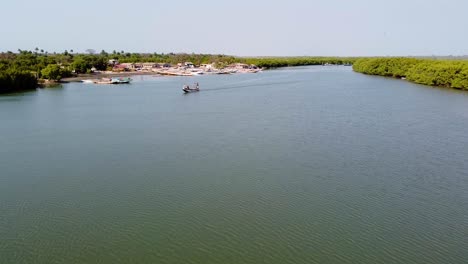 Aerial-drone-dolly-to-fishing-boat-in-river-Gambia-near-Kartong,-midday-sun