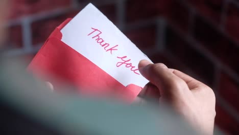 person opening a red envelope with a thank you note