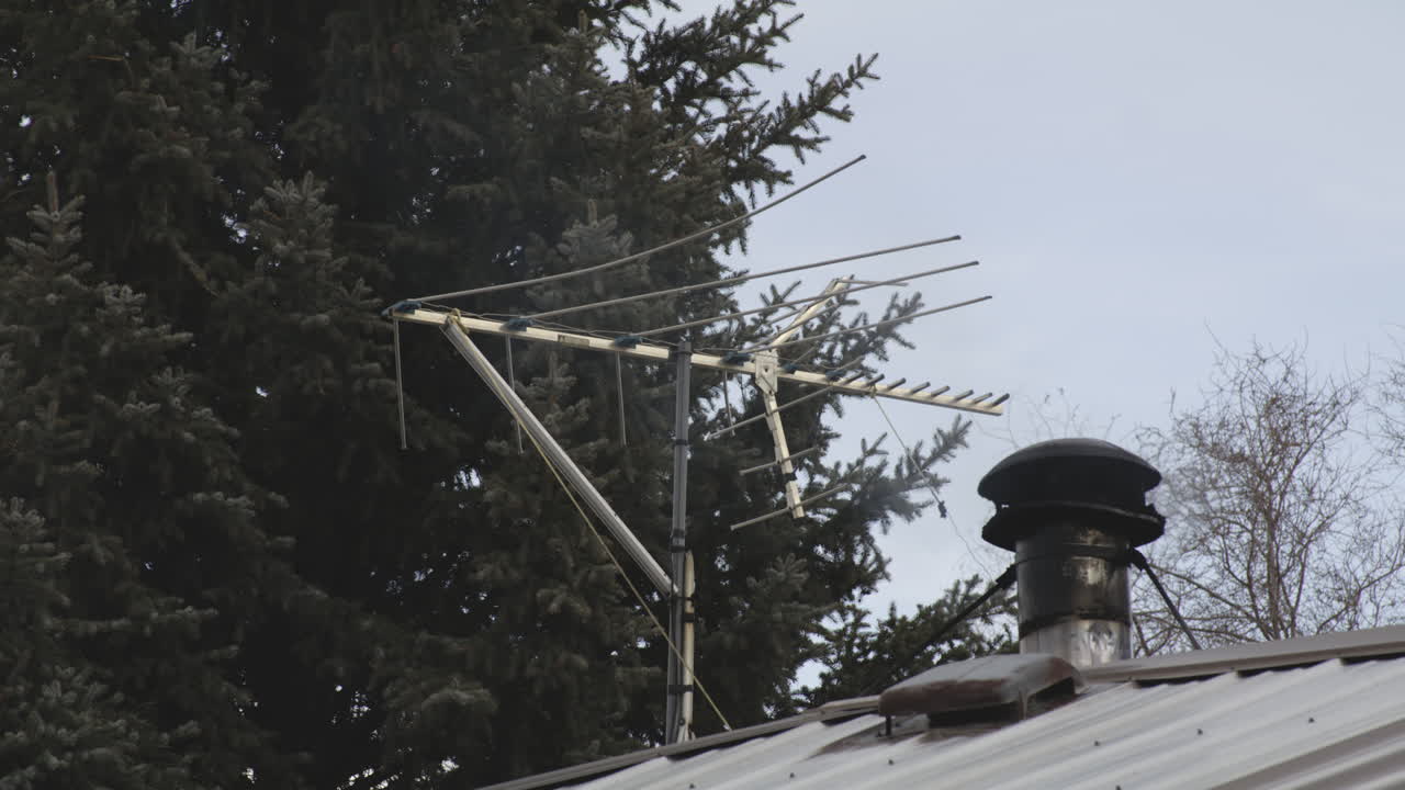antena de televisión con humo saliendo de la chimenea de la estufa en el techo de una casa
