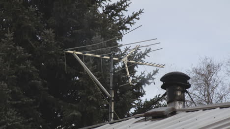 television antenna with smoke coming out in stove chimney on a house roof