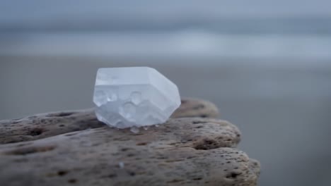 a beautifully carved white crystal glimmering on natural stones by the water’s edge, capturing the serenity of nature's artistic creations