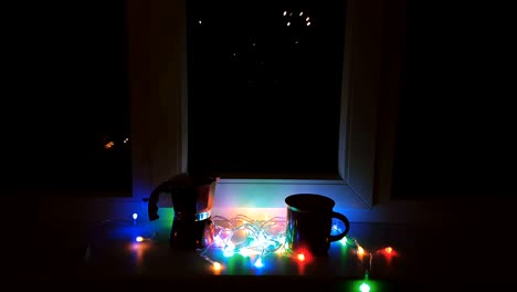 composición de navidad y año nuevo. taza de café, cafetera geyser roja y luces en el alféizar de la noche.