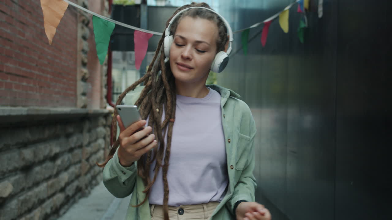 Woman Dancing and Listening to Music in a City Alley