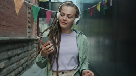 woman dancing and listening to music in a city alley