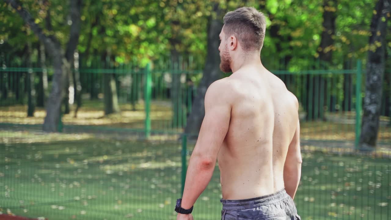 Muscular man posing on stadium. Strong serious handsome young sports man standing at stadium