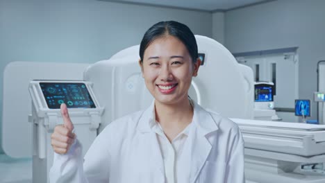 close up of asian woman doctor showing thumbs up gesture and smiling with mri machine in the hospital