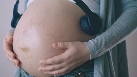mujer embarazada con auriculares en bailes de vientre en la habitación