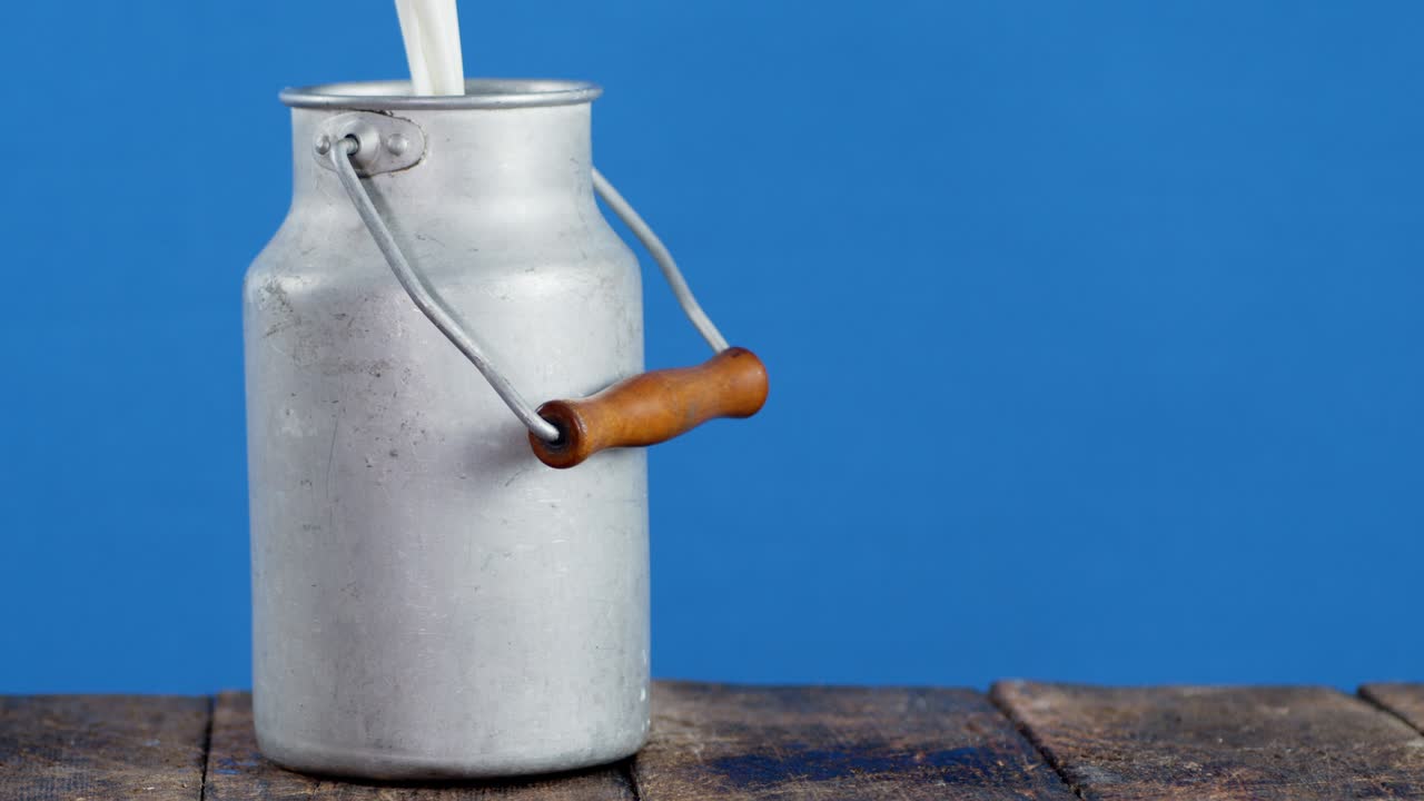 Milk pouring in a can on a wooden table.