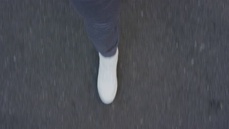 Mujer-Caminando-Por-Una-Carretera-Asfaltada-Con-Zapatos-Blancos-Paseando-Informalmente-En-La-Ciudad-Vista-Superior