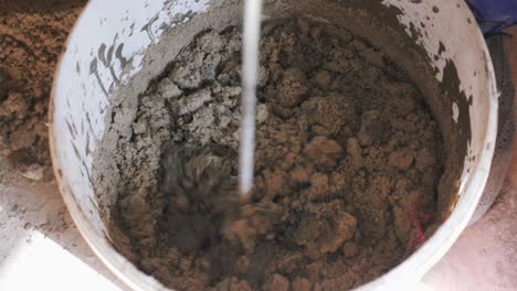 construction worker mixing concrete with water with drill for building. close up mixed cement in a mortar bucket