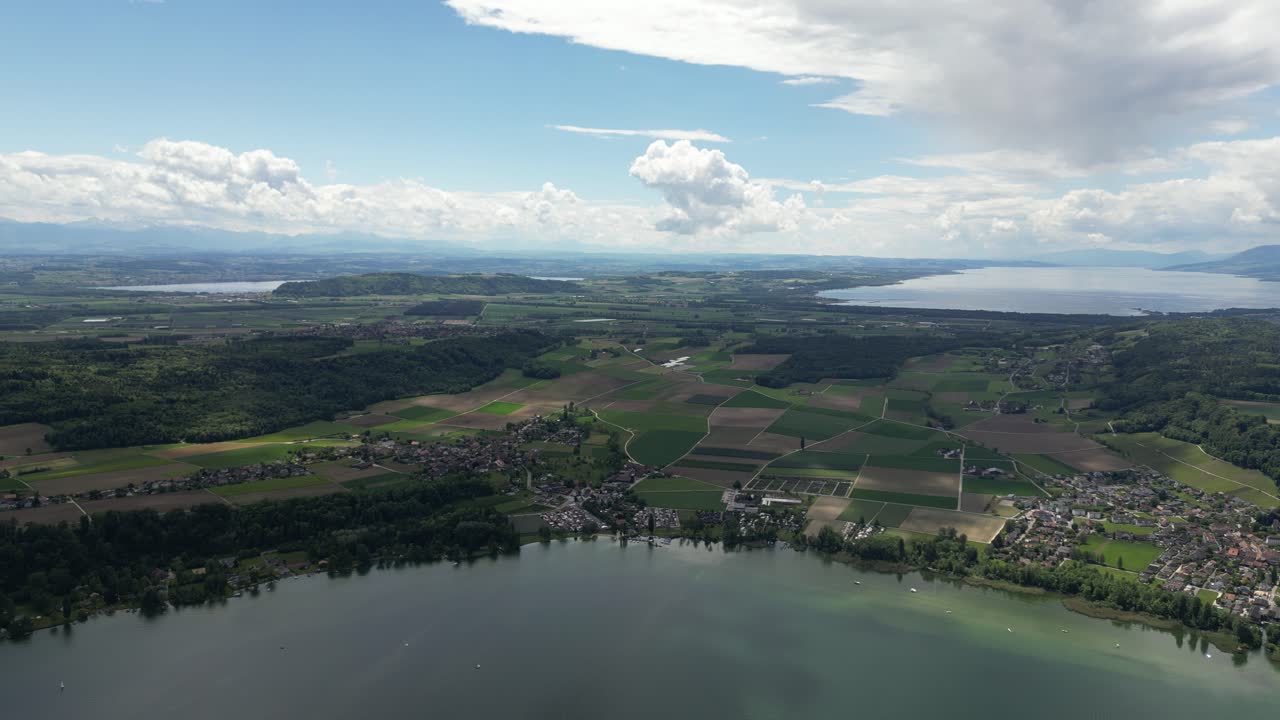 Comunità di un villaggio lacustre svizzero in riva al lago, paesaggio aereo naturale di colline e campi.