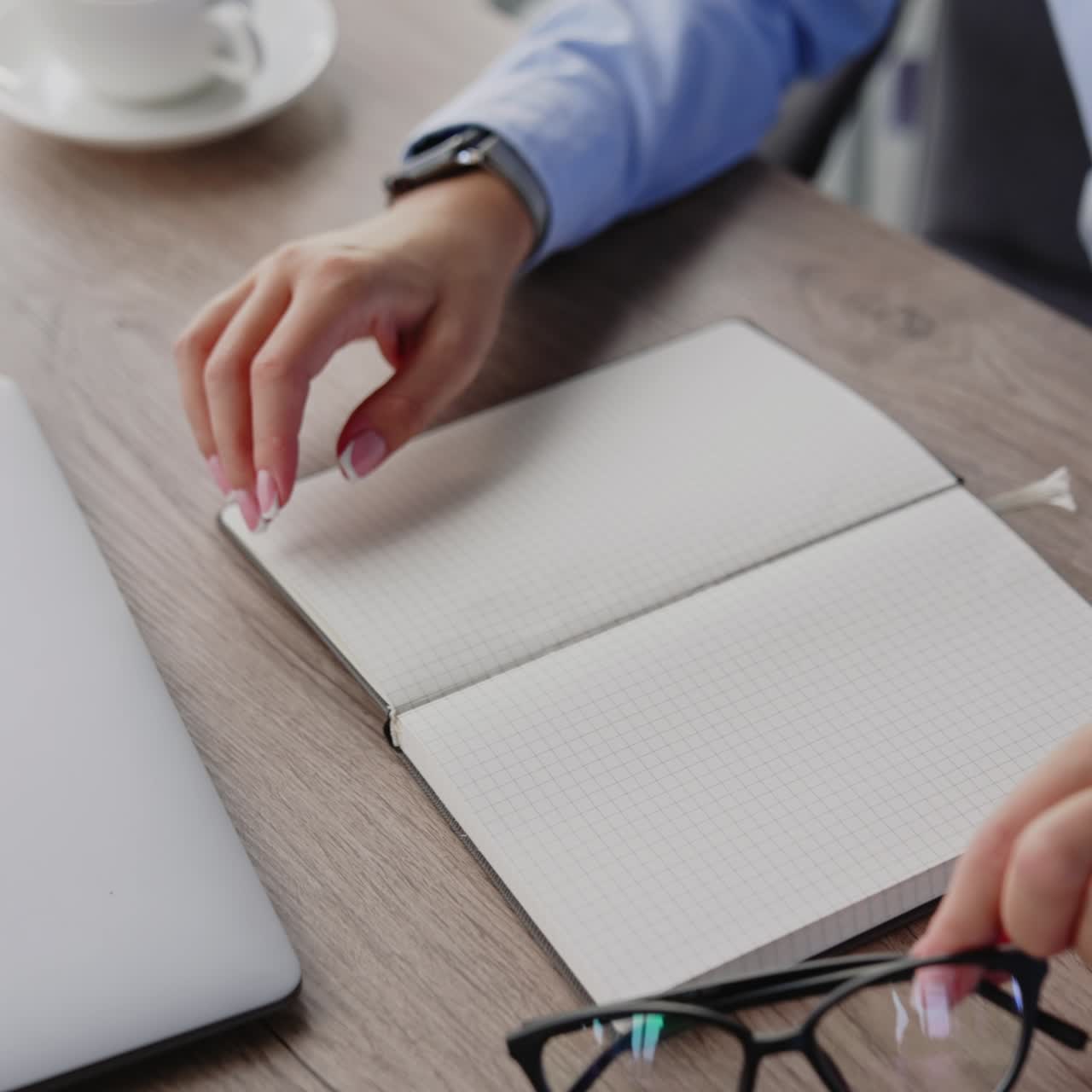 Female hands holding the glasses. Woman puts off the glasses and closes her paper notebook. Close up