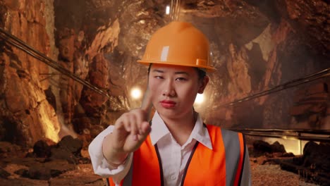 close up of asian female engineer with safety helmet disapproving with no index finger sign in underground mine tunnel