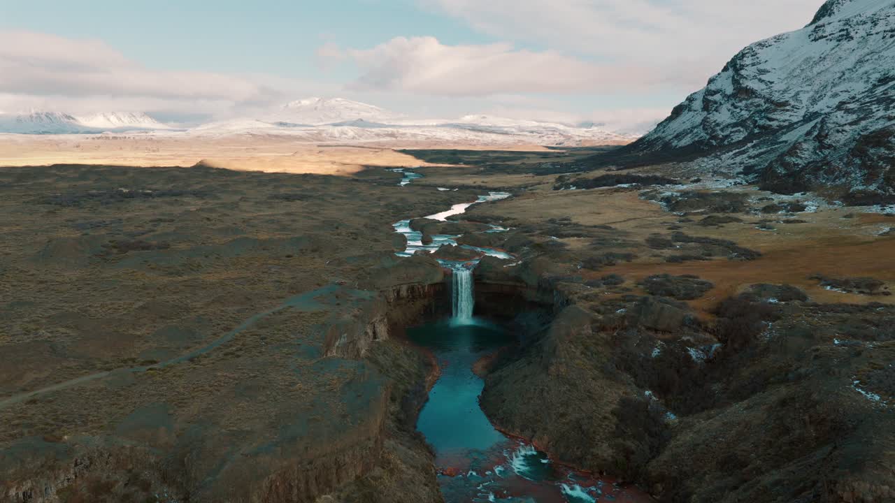 Aerial view of Salto del Agrio waterfall with turquoise river and snowy Andes mountains, Caviahue, Argentina