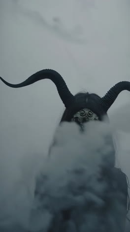 person in skull mask with horns in a mysterious setting