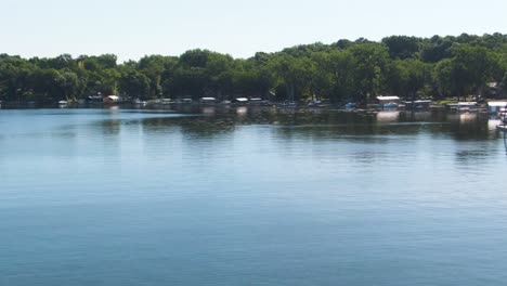 Shoreline-of-a-Calm-Lake-Showing-Boat-Lifts,-Boats,-Jet-Skis,-Pontoons,-Aerial-4K-Drone