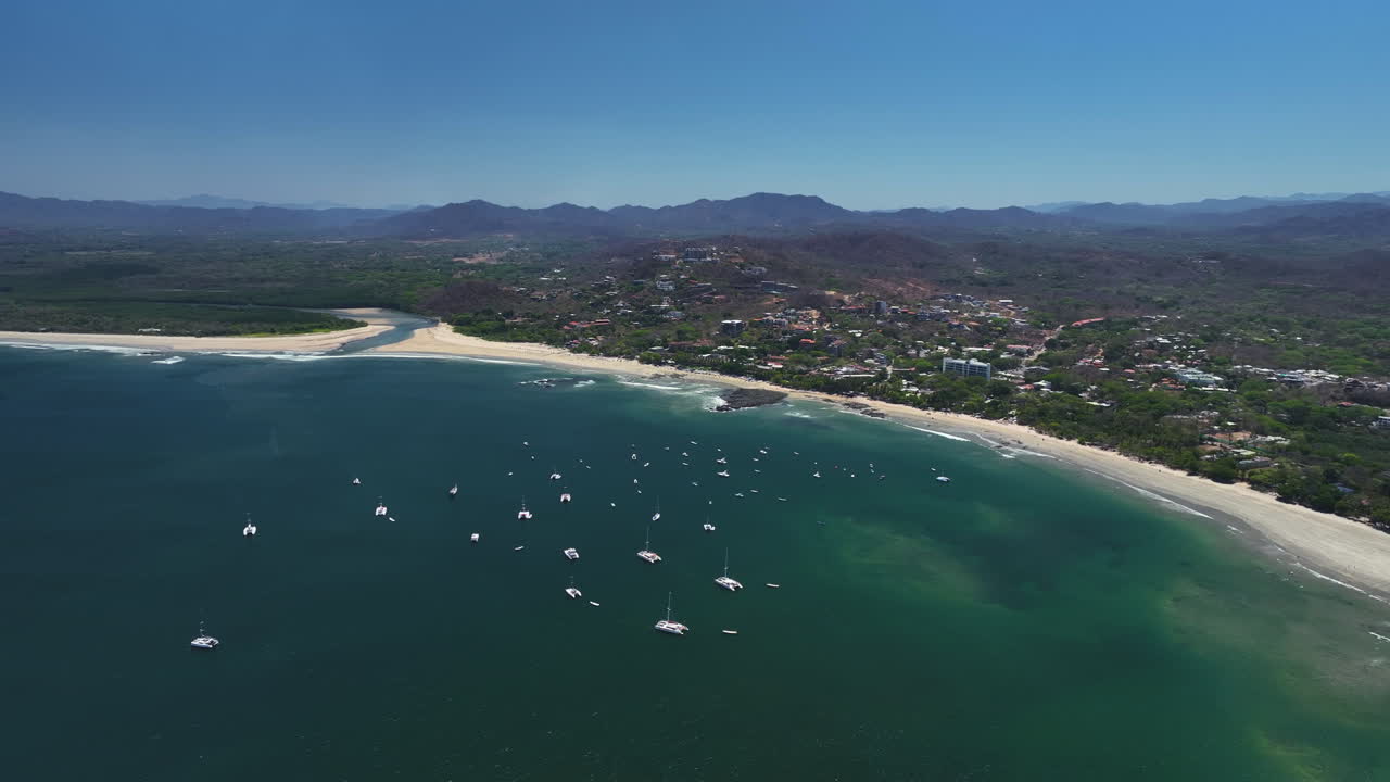 Panoramic drone shot of yachts anchored in front of Tamarindo beach, in Costa Rica