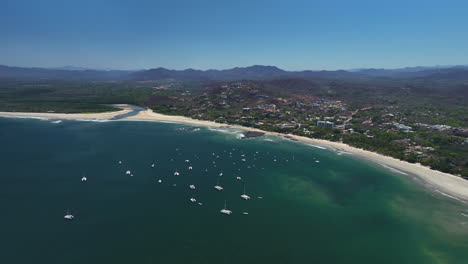 panoramic drone shot of yachts anchored in front of tamarindo beach, in costa rica