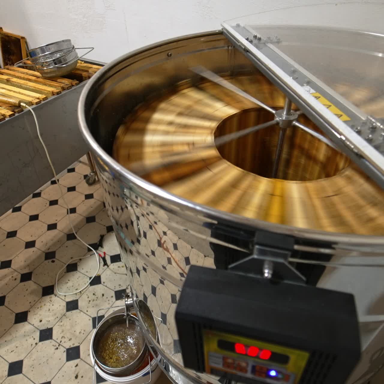 Automatic electric appliance for honey extraction working at the apiary. Big metal box full of frames standing beside