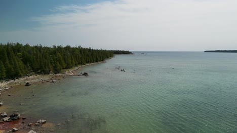 Aerial-view-up-forested-lake-coastline,-Les-Cheneaux-Island,-Michigan