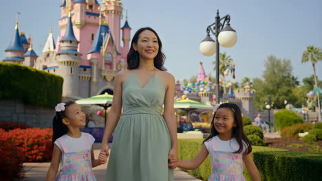 mother and daughters at a theme park with a castle