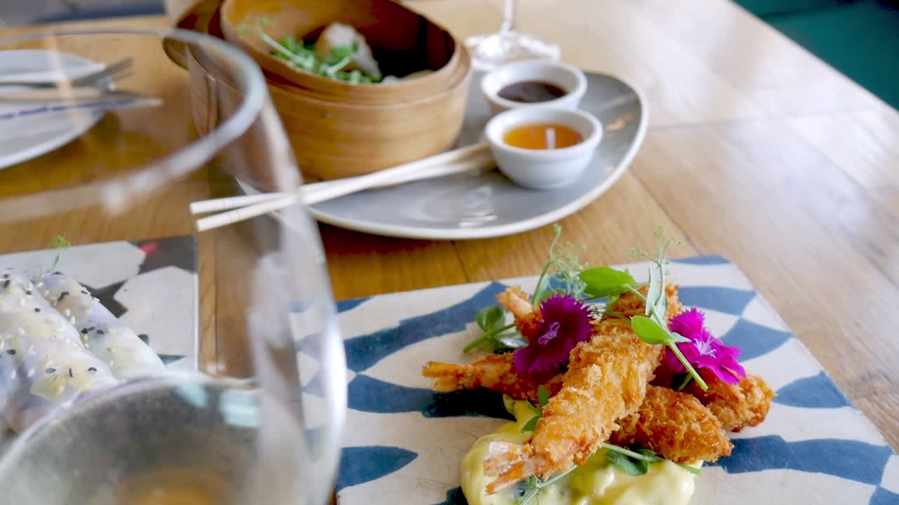 Tempura prawns served on blue tile and Dim Sum in bamboo steamer, close tilt-up